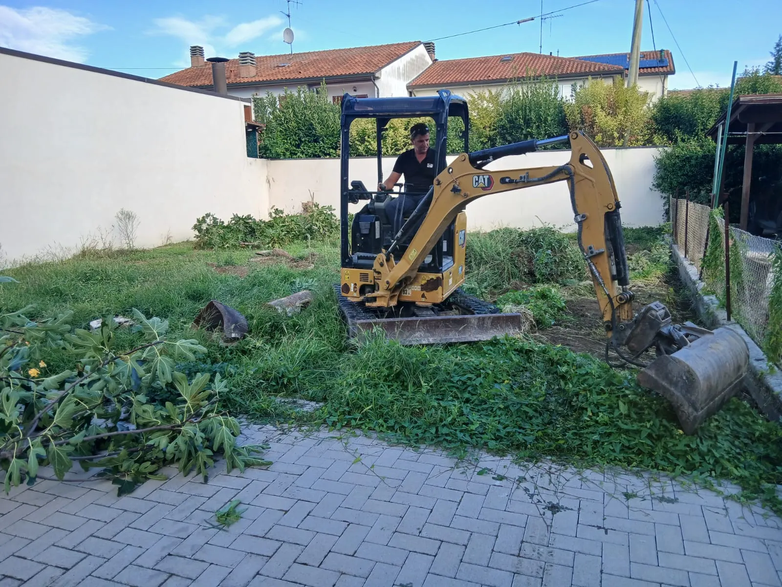 Miniescavatore che libera dalla vegetazione il giardino di una casa
